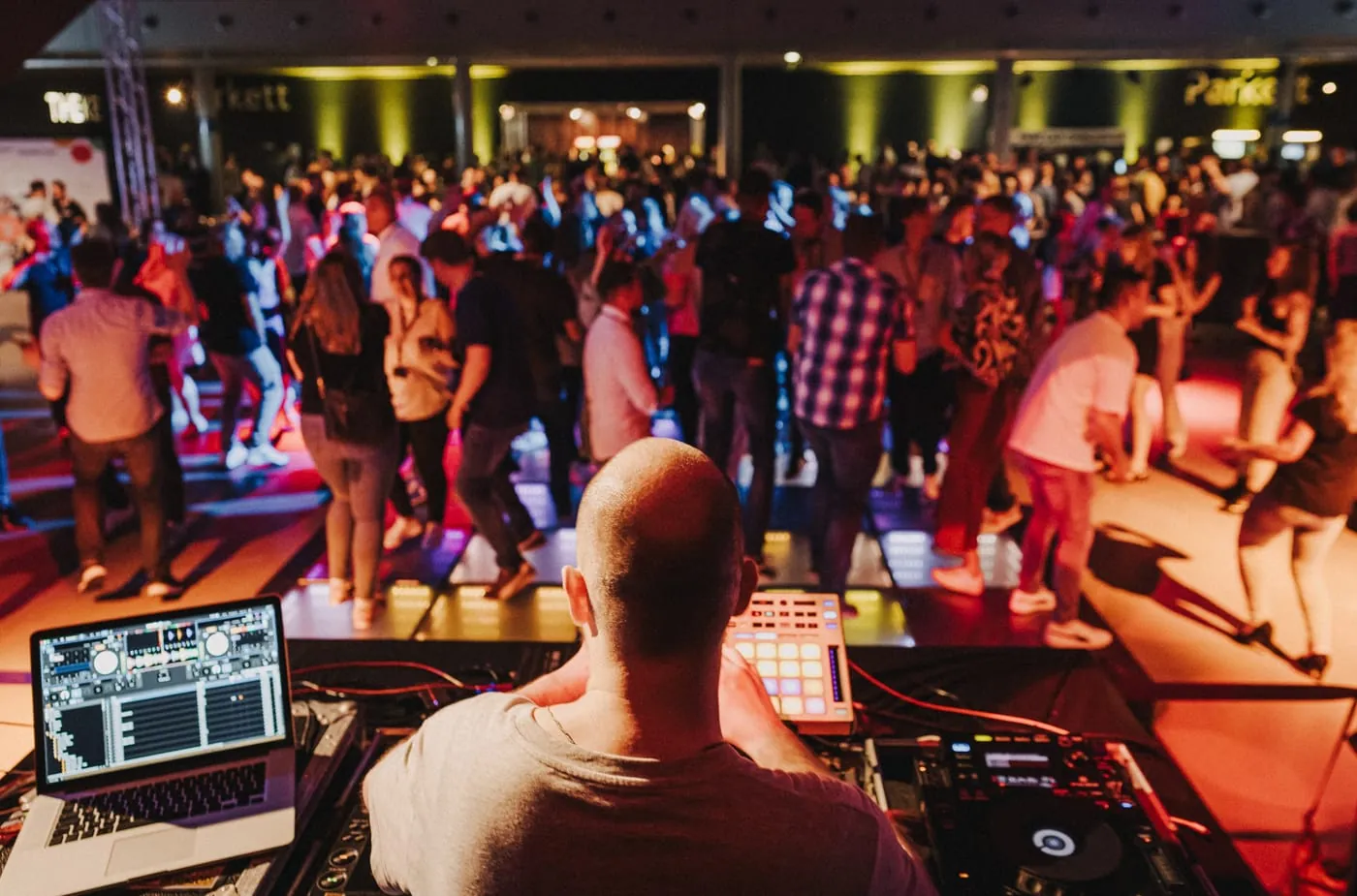 Bornd Fono von hinten am DJ-Pult mit Laptop und Controller, davor eine volle Tanzfläche bei einer Firmenfeier von EWE