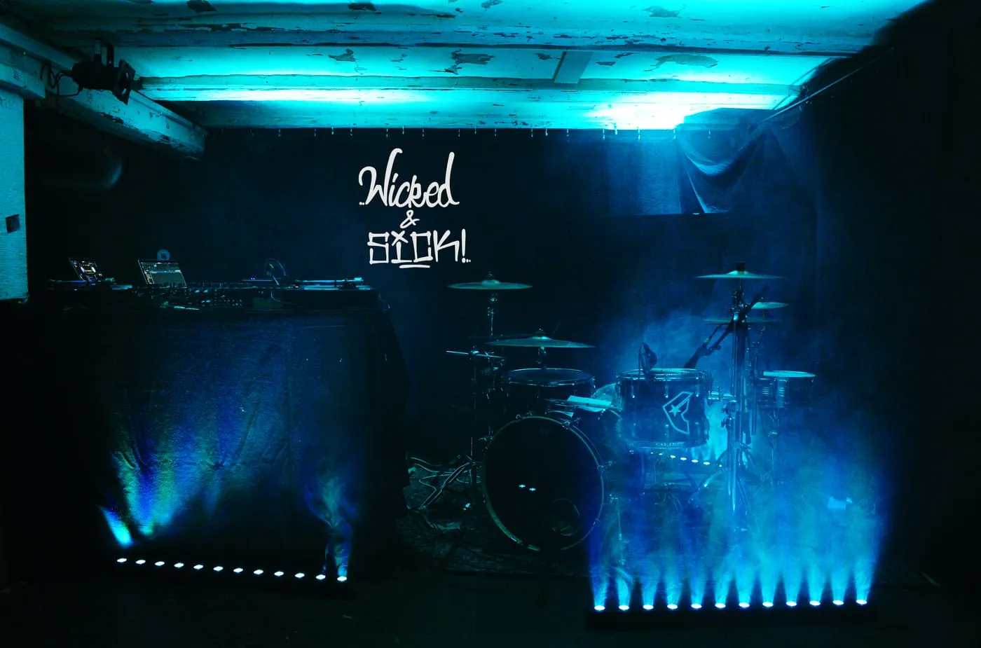 Bühne der Umbaubar in Oldenburg in blauem Licht und Nebel, aufgebaut für ein DJ-Set mit Schlagzeugbegleitung