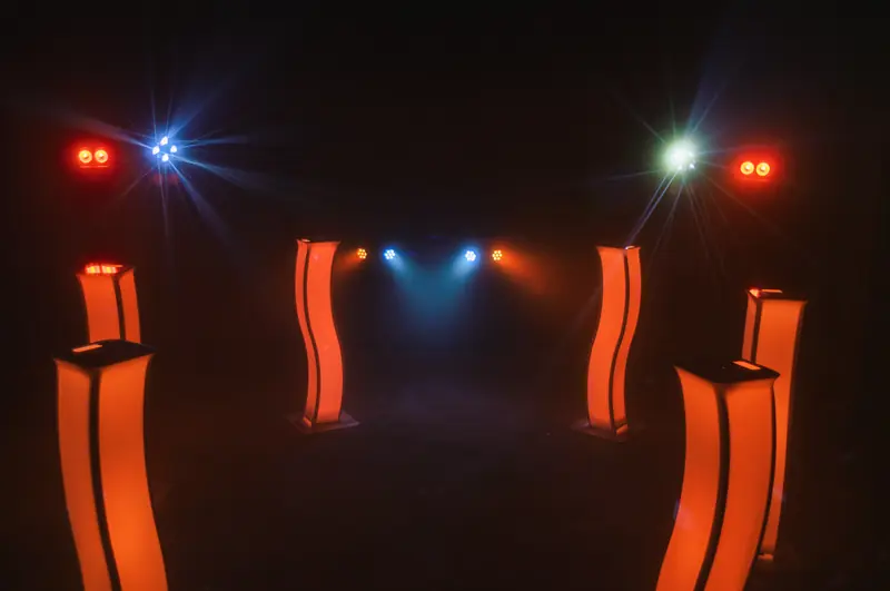 Sechs orange Leuchts&auml;ulen in zwei Reihen, dazwischen Scheinwerfer in Blau, Rot und Orange
