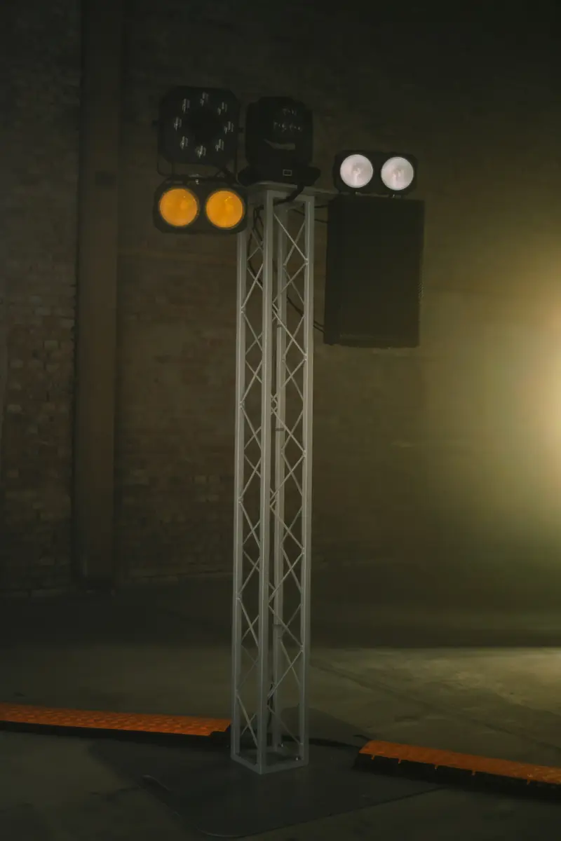 Traversenturm in voller H&ouml;he mit Scheinwerfern und Lautsprecher, die Kabel am Boden liegen unter orangen Kabelbr&uuml;cken